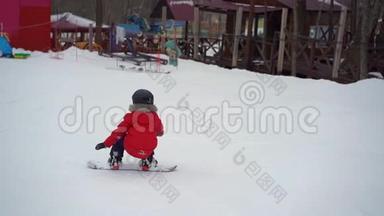 年轻人滑雪板教练教小男孩如何骑滑雪板。 冬季活动概念。 慢镜头